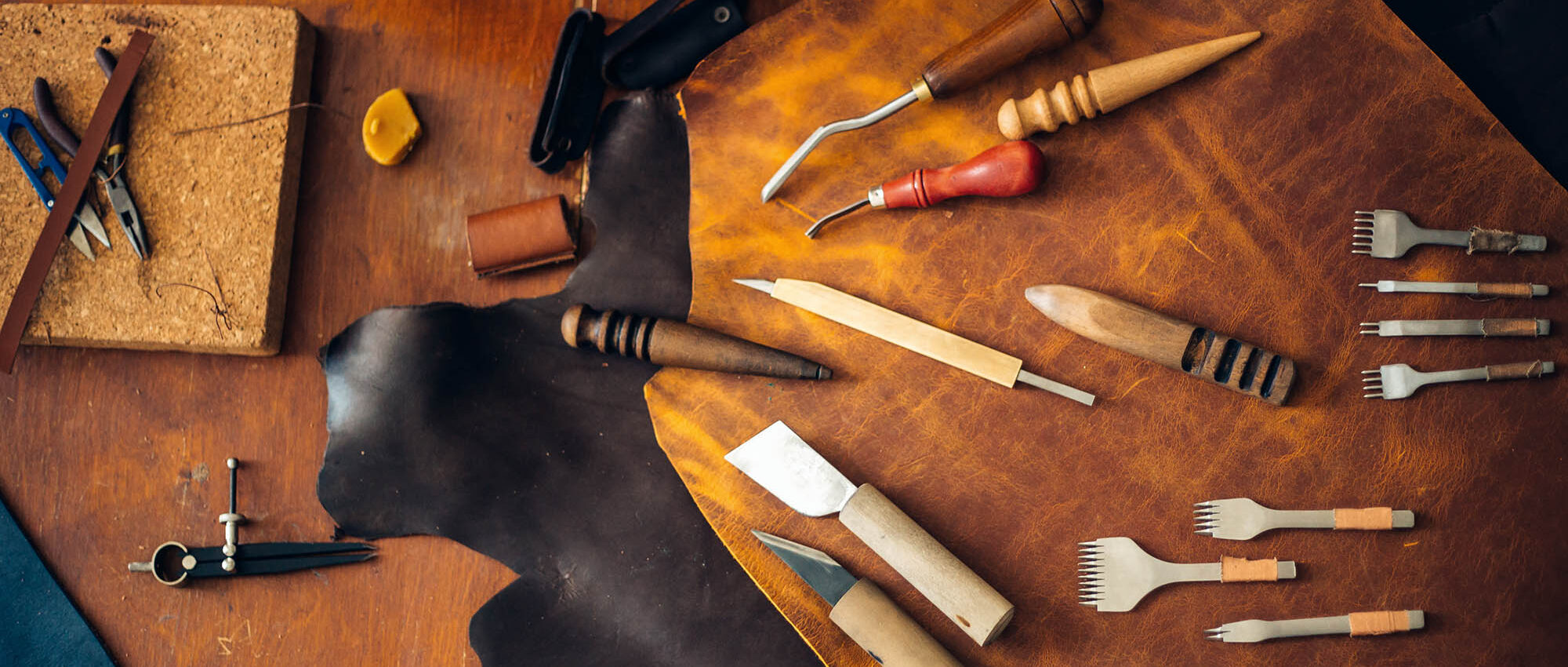 man doing leatherwork with leatherworking tools on table