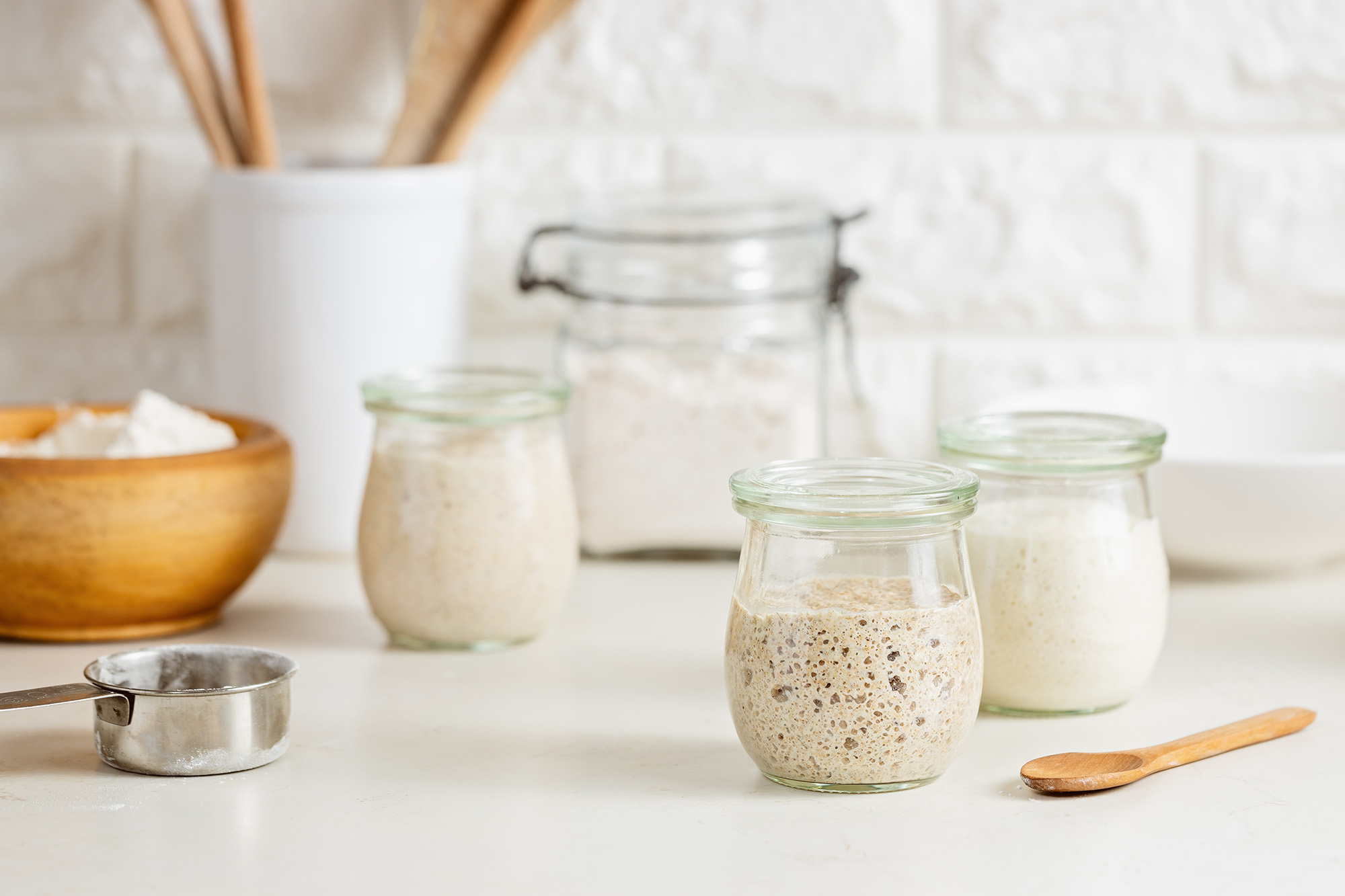 sourdough starter in a glass jar on a white counter